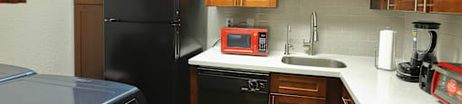 Kitchen area with light countertops, black appliances, and brown cabinets
