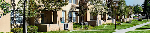 a row of apartments on a sidewalk with grass and trees