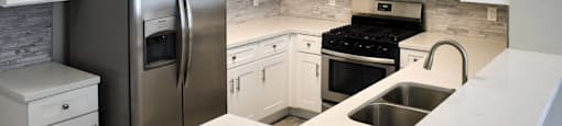 kitchen with light countertops, tile backsplash, stainless appliances, and white cabinets