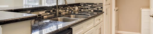 kitchen with dark countertops, in laid sink, and stainless appliances.
