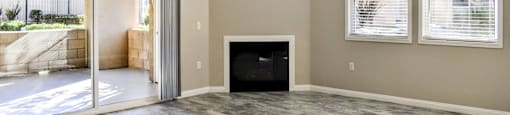 Living area with wood look flooring, two well lit windows, fireplace, ceiling fan, and access to private patio/balcony through sliding glass door