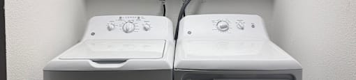 Two white washing machines in a laundry room.