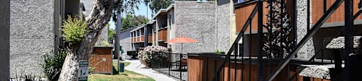 Exterior view of buildings with sidewalk leading past pool area and pet stations