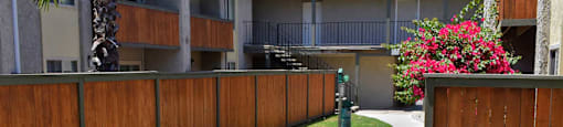 exterior view of buildings, private patios/ balconies, side walk winding through lush shrubbery and pet stations