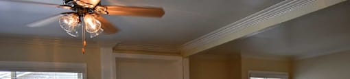 Living room with wood styled ceramic flooring, ceiling fan and windows