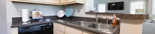 a kitchen with wooden cabinets and a black dishwasher and a sink