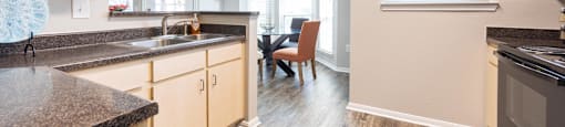 the view of a kitchen and living room with wood floors and granite counter tops