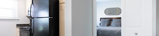 a bedroom with a black refrigerator and a door to a closet