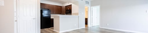an empty living room with a kitchen and a ceiling fan