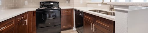 an empty kitchen with wooden cabinets and black appliances