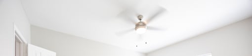 an empty living room with white walls and a ceiling fan