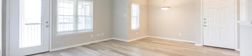 an empty living room with wood floors and a ceiling fan