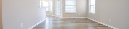 an empty living room with white walls and wood floors