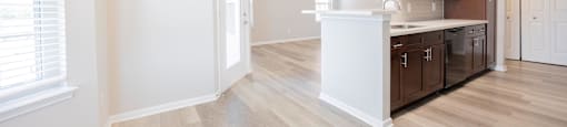 a renovated kitchen and living room with white walls and wood floors