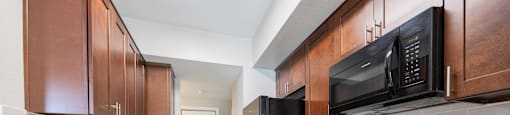 a kitchen with black appliances and wooden cabinets and white counter tops