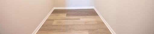 a walk in closet with white walls and wood flooring