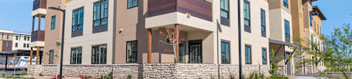 Exterior view of building with bushes and a sidewalk at Solace at Ballpark Village, Goodyear