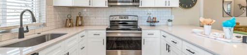 Open kitchen with white cabinets and stainless steel appliances at Solace at Ballpark Village, Goodyear, AZ