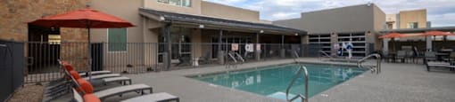 a pool with chairs and a building in the background at Inspiration Apartments, Cottonwood, AZ