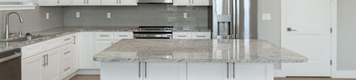 A kitchen with a granite countertop and stainless steel appliances.