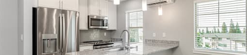 A modern kitchen with stainless steel appliances and a marble countertop.