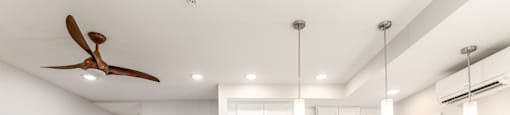 A modern kitchen with a wooden floor and a ceiling fan.