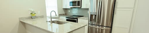 A kitchen with a granite countertop and stainless steel appliances.