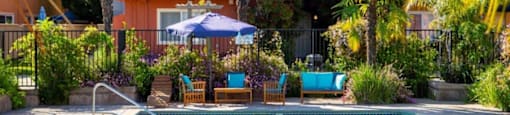 a pool with chairs and an umbrella in front of a building