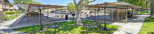 a park with trees and benches and a fenced in area