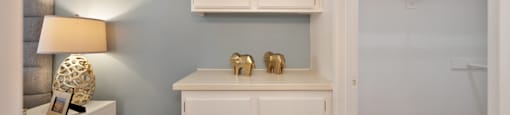 a living room with white cabinets and a desk with two gold elephants