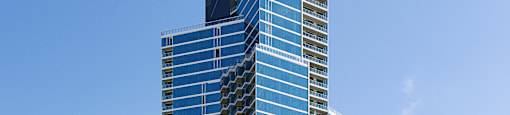 A tall blue building stands in front of a white dome and other buildings.