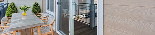 A table with chairs is on a balcony with a view of the outside.