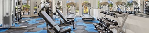 A gym with a variety of equipment including weights and benches.