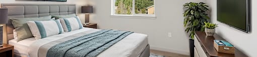 A bedroom with a large bed and a window showing trees outside.