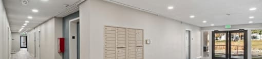 the upstairs hallway of a building with mailboxes and a exit sign