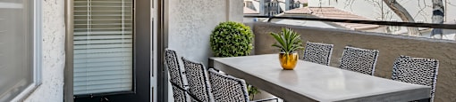 A table with chairs and a vase on it is on a balcony.