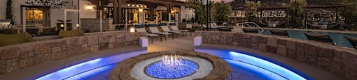 an outdoor fire pit at night with a building in the background