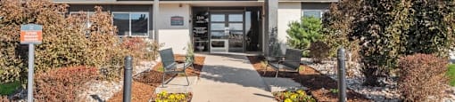 the front of a building with a walkway and benches in front of it
