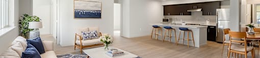 A modern living room with a large sofa, a coffee table, and a dining area.