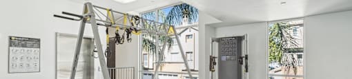 A gym with a weight bench, a pull up bar and a window.