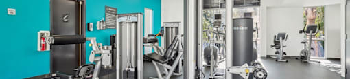 A fitness center with a variety of equipment including a squat rack, a leg press machine, and a bench press.