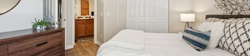 A bedroom with a large bed, a ceiling fan, and a wooden dresser.