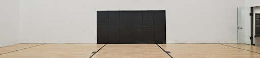 A basketball court with a hoop and a black wall.