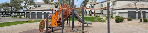 a playground with an orange swing set in front of a building