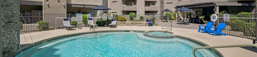 A swimming pool in front of a building with a blue sky in the background.