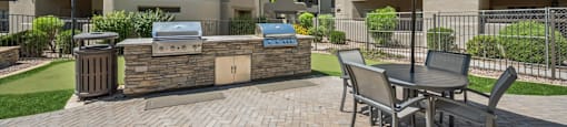 A patio with a table and chairs and a grill.