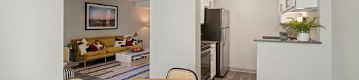 a dining room with a wooden table and a kitchen in the background