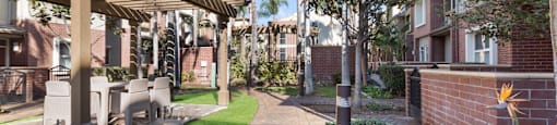A walkway with a pergola and a wall with a flower on it.