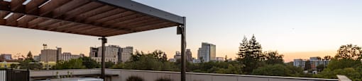 A wooden deck with a table and chairs overlooking a city skyline at dusk.