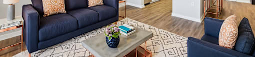 A living room with a blue couch and a painting on the wall.